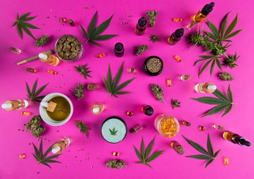 Bottles of cbd oil, marijuana and hemp leaves on pink background
