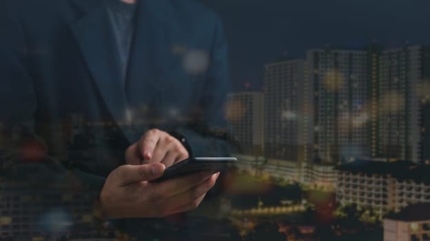 Hands holding a smartphone with a blurred urban Double exposure of Night city. Real estate concept business, home insurance and real estate protection