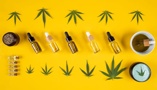 Set of essential oil in a glass bottle, with a pipette on a yellow background, top view