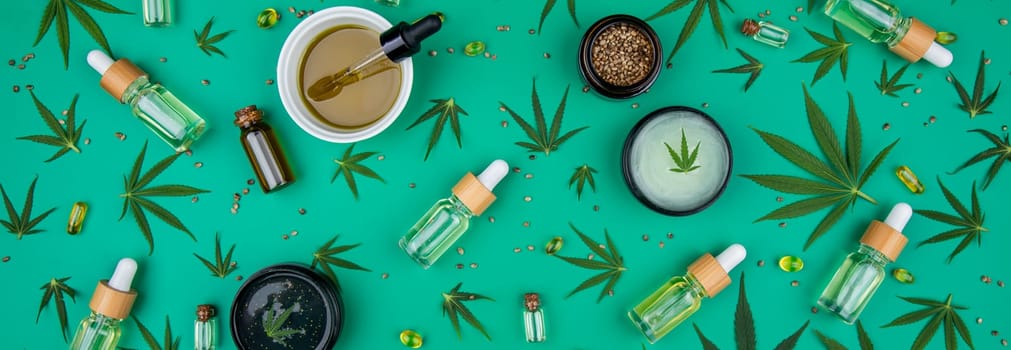 Flat lay composition with hemp oil and hemp leaves on green background