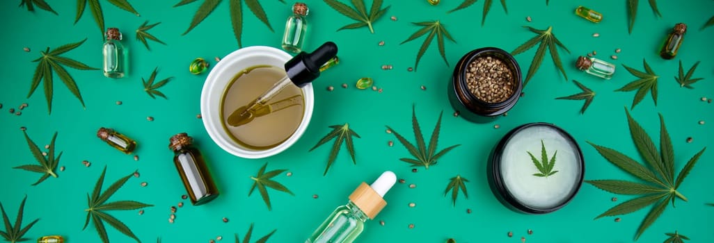 Flat lay composition of marijuana and hemp seeds on color green background