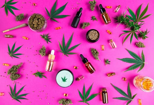 Bottles of cbd oil, marijuana and hemp leaves on pink background