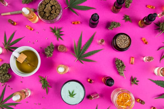 Bottles of cbd oil, marijuana and hemp leaves on pink background