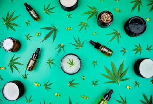 Flat lay composition with hemp oil and hemp leaves on green background
