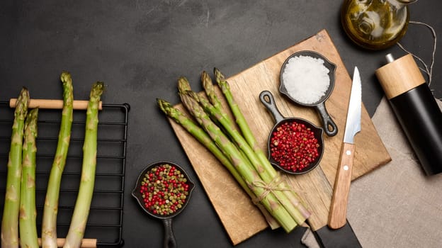Fresh green asparagus sprouts on a black wooden background. View from above