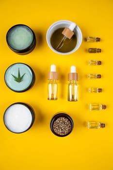Set of essential oil in a glass bottle, with a pipette on a yellow background, top view