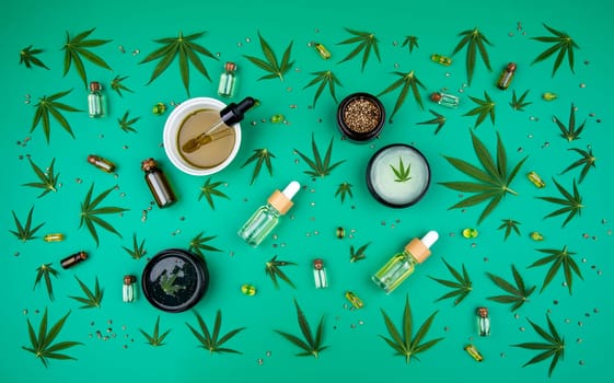 Flat lay composition with hemp oil and hemp leaves on green background