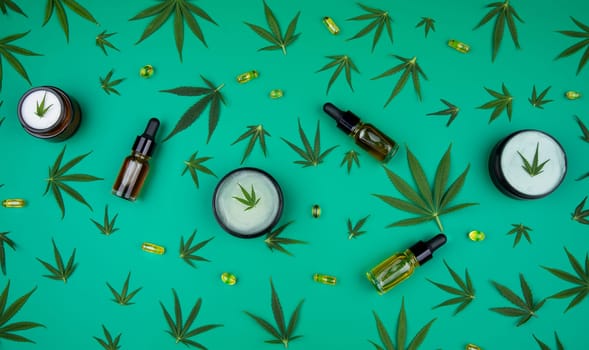 Flat lay composition with hemp oil and hemp leaves on green background