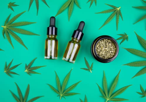 Flat lay composition of marijuana and hemp seeds on color green background