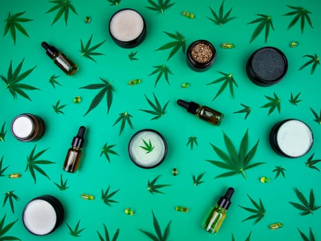 Flat lay composition with hemp oil and hemp leaves on green background