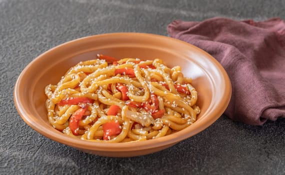 Bowl of udon noodles with bell pepper and mushrooms