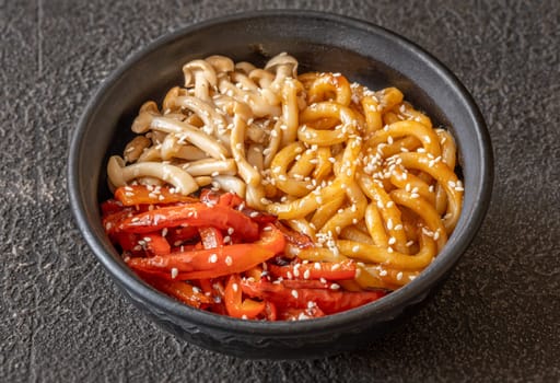 Bowl of udon noodles with bell pepper and mushrooms