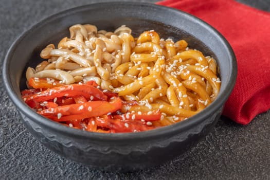 Bowl of udon noodles with bell pepper and mushrooms