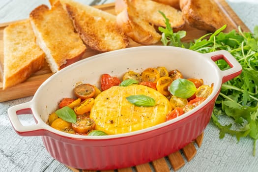Baked camembert cheese with cherry tomatoes and basil