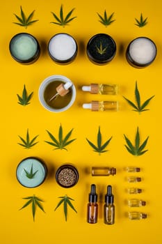 Set of essential oil in a glass bottle, with a pipette on a yellow background, top view