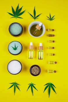 Set of essential oil in a glass bottle, with a pipette on a yellow background, top view