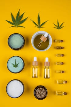 Set of essential oil in a glass bottle, with a pipette on a yellow background, top view