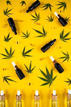 Set of essential oil in a glass bottle, with a pipette on a yellow background, top view