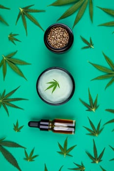Flat lay composition of marijuana and hemp seeds on color green background
