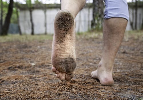 Detail of bare feet walking through nature, dirt