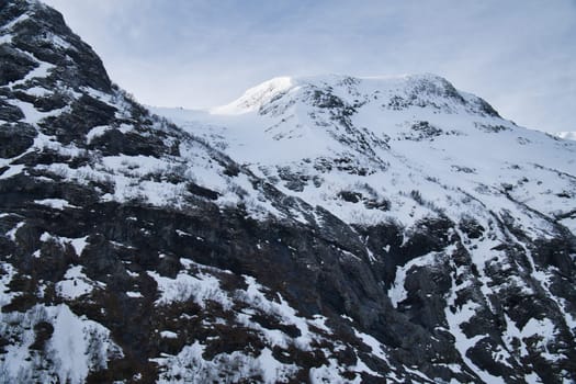 Norwegian landscape. The road leads through a mountain gorge that descends from the glacier. Rough nature in Scandinavia. Landscape photo from the north