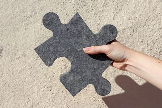 A woman holds a large stone puzzle piece in her hand