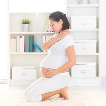 Late pregnant Asian woman having shoulder pain at home. Pregnancy health care concept.
