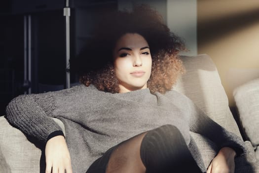Young woman savoring a peaceful moment at home, relaxing on her cozy sofa, enjoying alone time in her warm living room. Captures self care and mental wellbeing in everyday life