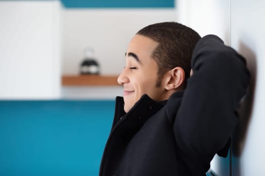 Young man is enjoying a moment of peace and quiet in his modern home, his eyes closed as he takes a break from his busy day