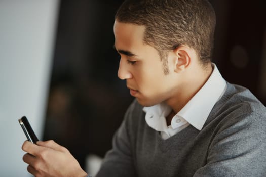 Young businessman multitasks on his smartphone in a cozy home office, embodying modern technology and remote work