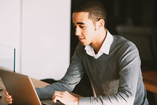 Young man works on his laptop in a cozy home office, balancing work and life seamlessly with remote flexibility