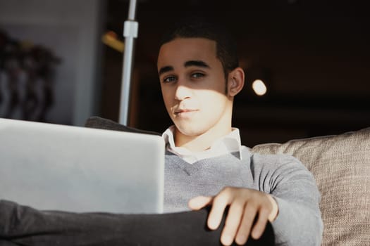 Young professional man works from home on his laptop, soaking up sunlight in a cozy office setup