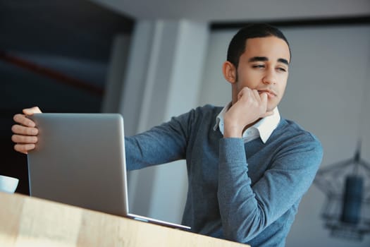 Young businessman is closing his laptop after a long day of work, deep in thought about the challenges and opportunities that lie ahead