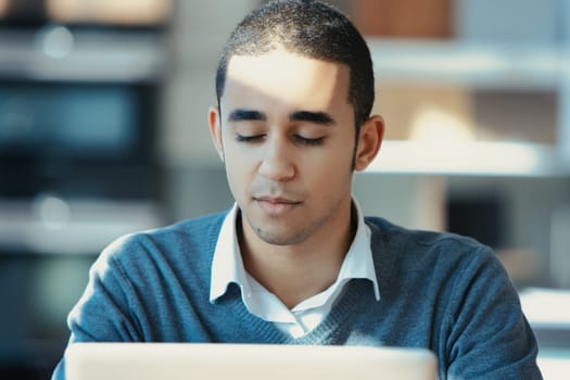 Young man deeply focused on his laptop in a cozy home office, showcasing determination and ambition in remote work