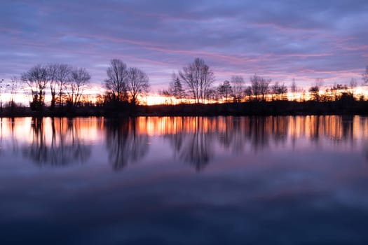 Nightscape photo of Adour French river after blazing red sunset with dramatic clouds floating. Real photography