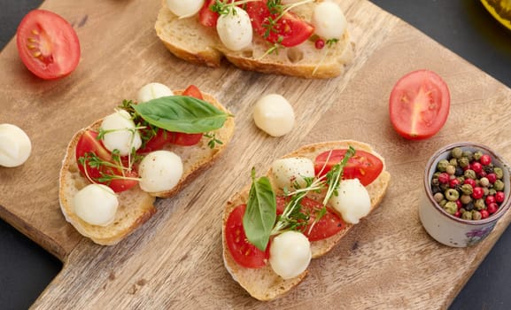 Round mozzarella, cherry tomatoes and microgreens on a piece of white bread, a healthy sandwich