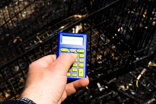 Blue calculator in dark soil, burnt ground after a fire