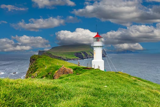 White lighthouse  green grass field mykines faroe island cloudy sky