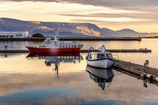 Two boats reflecting  water reykjavik harbor sunset  mountains background