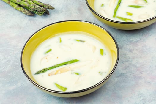 Dietary cream soup with white and green asparagus in bowl .