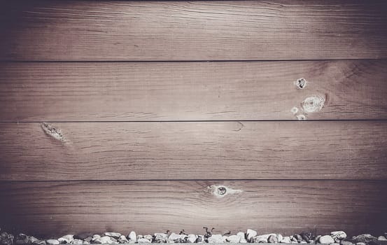 Rustic wooden planks with visible fibers and knots, as well as small pebbles at the bottom, background image
