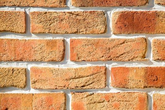 Close-up of a brick wall with a textured surface in shades of orange and red, background image