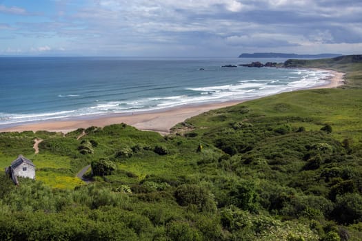 White Park Bay (also spelled Whitepark Bay) has three-mile long beach near Ballycastle, County Antrim on the north coast of Northern Ireland. Sheep and cattle graze the hills and beach along the bay, which has been under the care of the National Trust for Places of Historic Interest and Natural Beauty since 1938