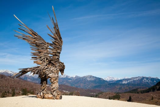 Wooden sculpture of an eagle made of tree branches. Vaia storm eagle
