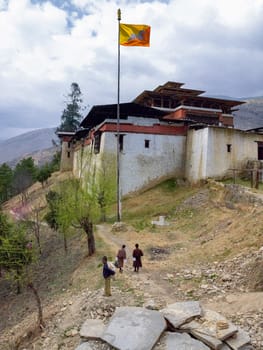 Flag of Bhutan flying above a Buddhist Dzong (monastery) in the Kingdom of Bhutan high in the Himalayas.
