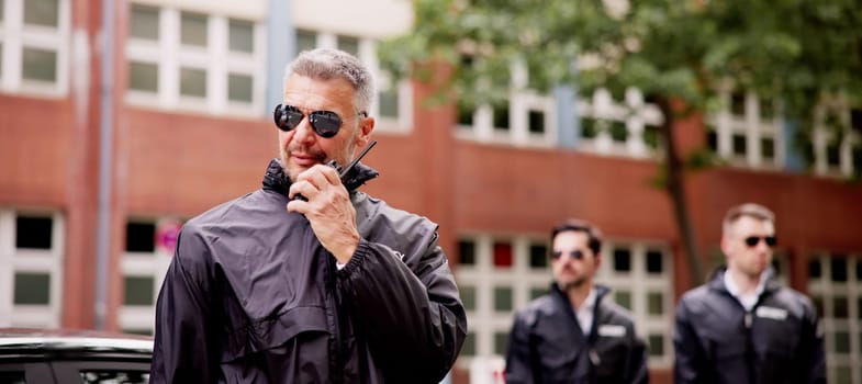 VIP Security Officer Safeguarding Luxury Car Business Client Outside Corporate Event with Walkie-Talkie Protection Services for High-End Executives.