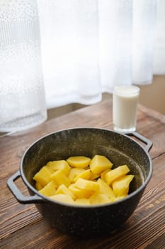 Kitchen table with boiled potatoes in a pot and glass of warm milk