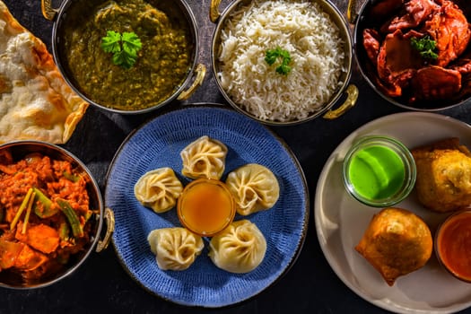 Composition with indian dishes: samosa, pakora, palak paneer, jalfrezi, thukpa and naan bread