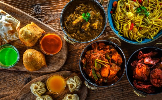 Composition with indian dishes: samosa, pakora, palak paneer, jalfrezi, thukpa and naan bread
