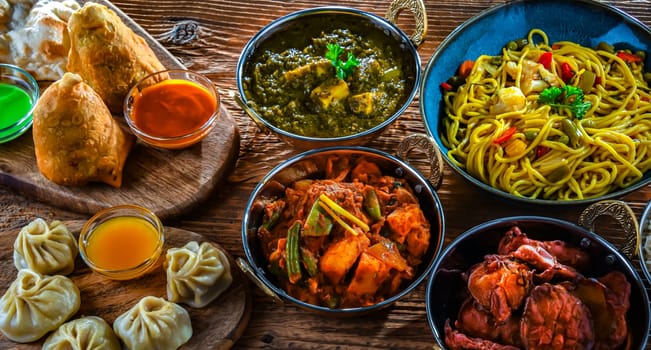 Composition with indian dishes: samosa, pakora, palak paneer, jalfrezi, thukpa and naan bread